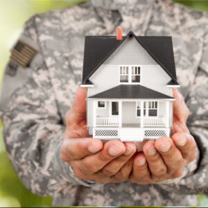 military person holding model home in hands